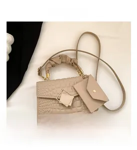 Detail view of beige crocodile embossed handbag with cloud handle and envelope coin purse