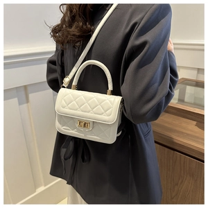 Détail d'un petit sac bandoulière blanc matelassé avec fermoir doré porté par mannequin