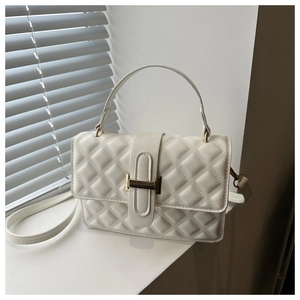 Detailed view of the white quilted texture and golden rectangular buckle on the handbag