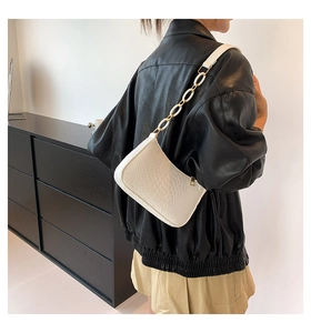 Detail showing the white animal-embossed texture and golden chain strap of the shoulder bag