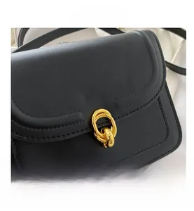 Close-up of black crossbody bag featuring a golden double-ring interlocking metal buckle