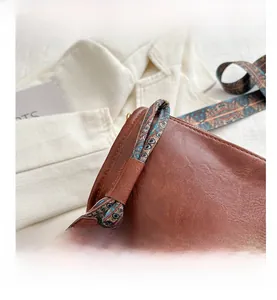 Close-up of brown vintage leather bag with ethnic geometric pattern wide strap and rivets