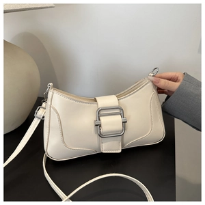 Détail du sac baguette en cuir crème avec boucle en métal argenté et bandoulière fine