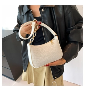 Close-up of a white croc-embossed baguette bag with stylish large gold chain ring details