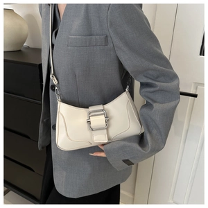 Détail du sac baguette blanc crème avec boucle argentée porté avec un blazer gris