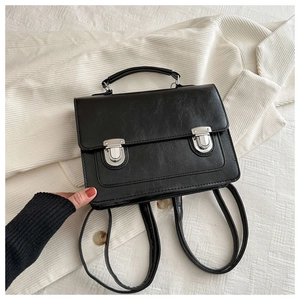 Détail d'un sac à dos vintage en cuir PU noir avec boucles argentées sur tissu rayé
