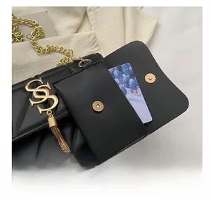 Détail d'un sac matelassé noir avec pompon doré en S et pochette à cartes amovible