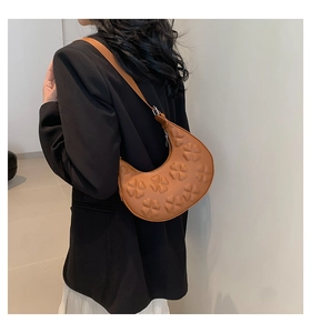 Détail d'un sac à bandoulière croissant marron avec texture de trèfle en relief 3D