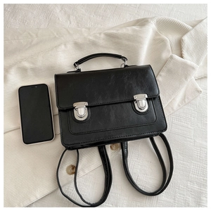 Détail d'un sac à dos vintage noir à côté d'un smartphone pour comparer les dimensions réelles