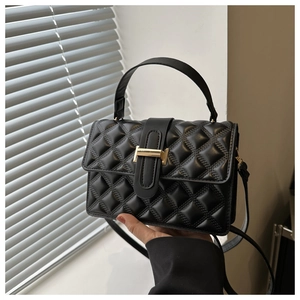 Detail of black quilted crossbody bag with golden metal buckle and premium texture