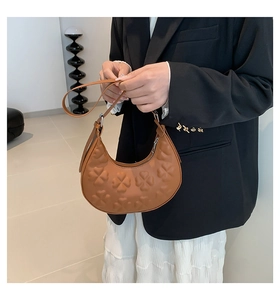 Detailed close-up of brown hobo bag with embossed clover pattern and smooth leather strap