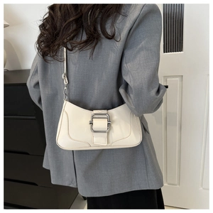 Sac baguette chic blanc cassé avec boucle argentée porté sur un blazer gris pour le style