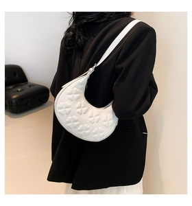 Close-up of a white hobo bag with embossed floral texture on a black blazer background