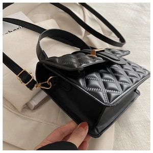 Detail of black quilted small square bag with golden buckle and sleek leather texture