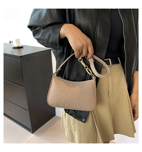 Detail of khaki crocodile pattern shoulder bag with golden oval chain on leather strap