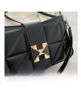 Close-up of geometric quilted black leather bag featuring a gold H-shaped buckle clasp