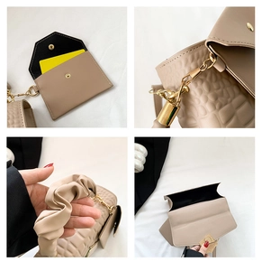 Detail view of beige crocodile embossed handbag with pleated handle and mini card pouch