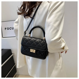 Détail du sac matelassé noir avec fermoir rotatif doré et poignée incurvée élégante