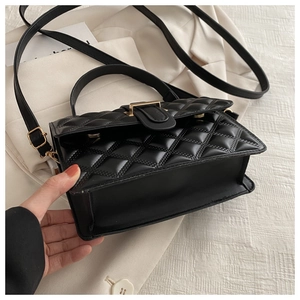 Close-up of black quilted shoulder bag with gold hardware and rhombic stitching details