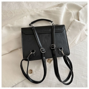 Vue arrière du sac en cuir PU noir avec garniture argentée sur un blazer rayé
