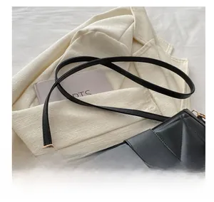 Detail of adjustable leather strap and golden H-shaped buckle on black quilted bag