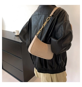 Detail showing beige croc-embossed underarm bag with thick matte resin chain strap