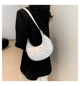Detailed texture of white half-moon shoulder bag with embossed floral clover pattern