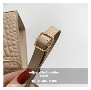 Detail of beige crocodile pattern bag with an adjustable golden square buckle strap