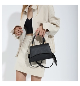 Détail de la texture cuir crocodile sur le sac à main noir avec une poignée tressée