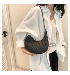 Détail latéral du sac croissant noir avec motif trèfle en relief et fermeture éclair chic