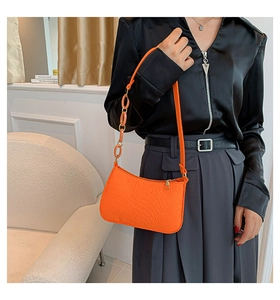 Detail of bright orange faux crocodile leather baguette bag with chain and shoulder strap