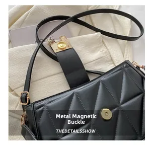 Detail of golden magnetic snap closure on black quilted faux leather crossbody handbag