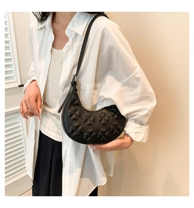 Detail showing the 3D clover embossed texture on black leather half-moon shoulder bag