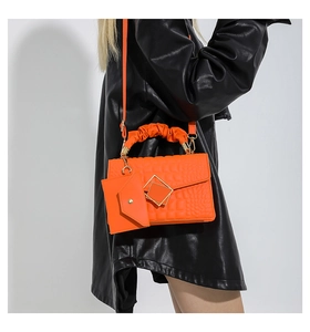 Detail of orange crocodile pattern crossbody bag with mini envelope pouch and gold buckle