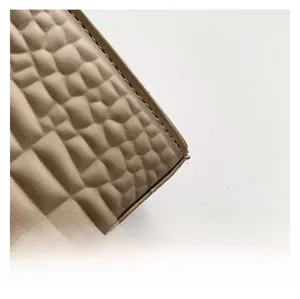 Close-up of khaki crocodile-embossed leather texture with precise stitching details