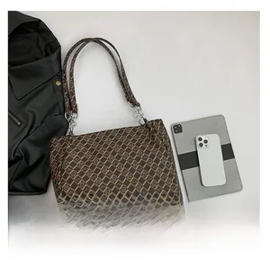 Detail of a large capacity brown monogram tote bag showing textured canvas and chain strap