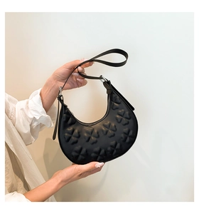 Detail of black half-moon hobo bag featuring 3D embossed clover patterns on faux leather