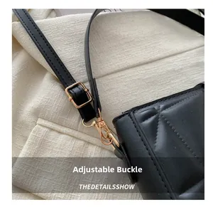 Detail of golden adjustable buckle and quilted leather texture on a black crossbody bag