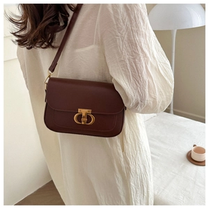 Détail du sac bandoulière en cuir mat marron avec boucle élégante en métal doré