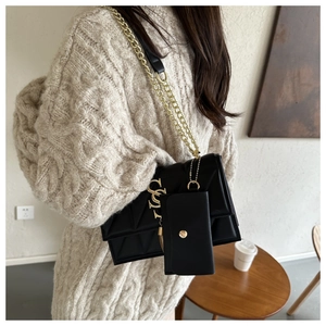 Detail of black quilted leather shoulder bag with gold SY logo and mini coin purse charm