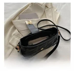Detail view of the black quilted crossbody bag with gold hardware and interior zip pocket
