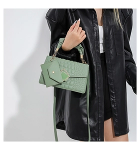 Detail of light green crocodile embossed handbag with pleated handle and mini pouch charm