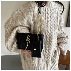 Detail of black quilted shoulder bag featuring gold S-buckle and fringe tassel decoration