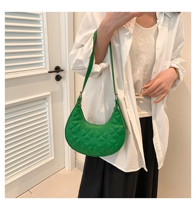 Detail of light green crescent shoulder bag with embossed four-leaf clover pattern