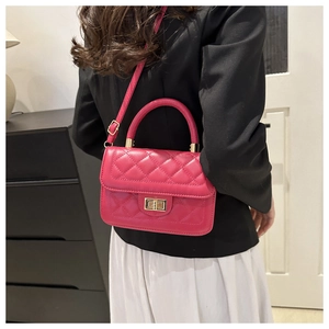 Détail du sac matelassé rose rouge avec fermoir doré porté sur robe blanche