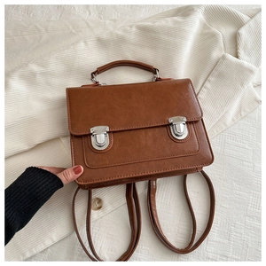 Détail d'un sac à dos vintage marron avec boucles argentées sur tissu texturé beige
