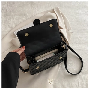 Detail of black quilted shoulder bag with gold magnetic buckle and interior space view