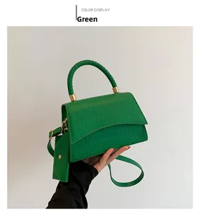 Detail of green crocodile texture handbag with woven handle and matching mini coin purse