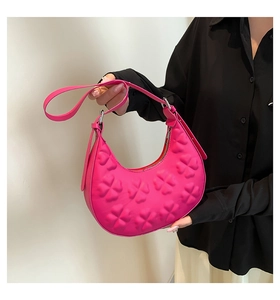 Detail of bright pink half-moon bag featuring embossed clover texture and silver metal hardware