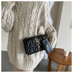 Quilted black chain shoulder bag with gold S logo and fringe detail on knit sweater